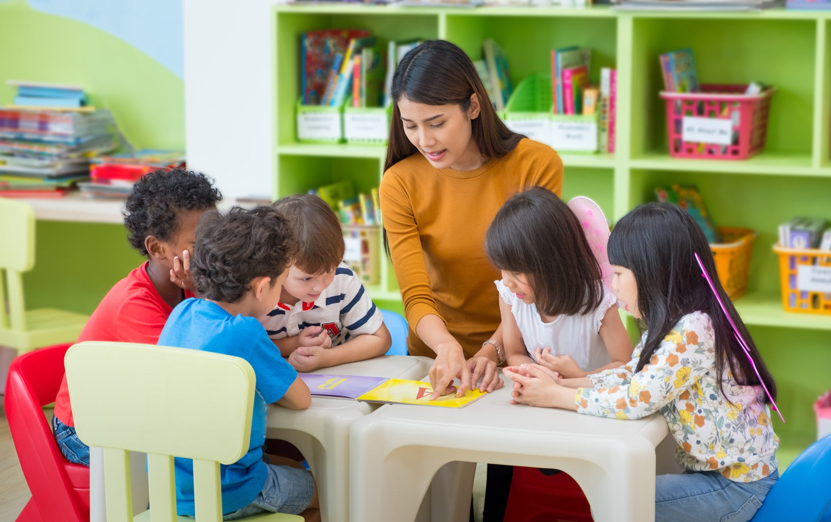 Eine Erzieherin erklärt einer Gruppe Kindern eine Aufgabe